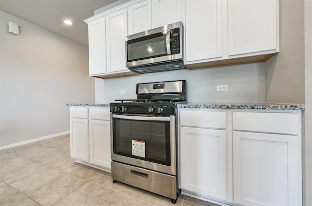 kitchen with light tile patterned flooring, stone counters, stainless steel appliances, and white cabinetry