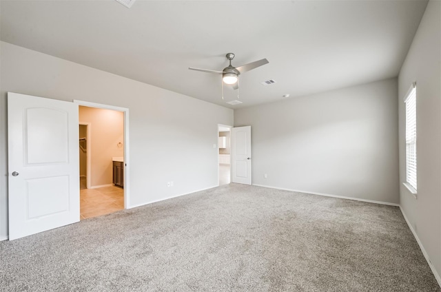 unfurnished bedroom with ceiling fan, light carpet, and connected bathroom