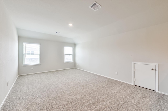 spare room featuring light carpet and lofted ceiling