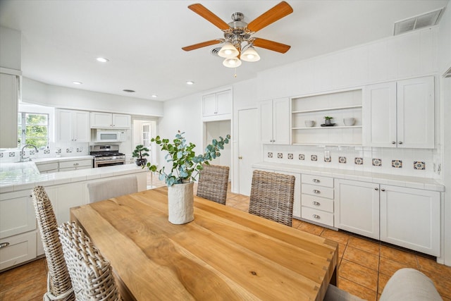 tiled dining room featuring ceiling fan and sink