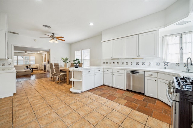 kitchen with appliances with stainless steel finishes, white cabinets, decorative backsplash, light tile patterned floors, and ceiling fan