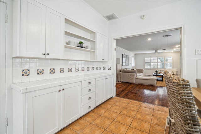 kitchen with white cabinetry, tile countertops, light tile patterned floors, and decorative backsplash