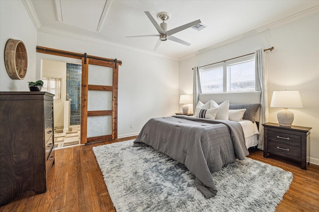 bedroom featuring ornamental molding, dark hardwood / wood-style floors, ceiling fan, and a barn door