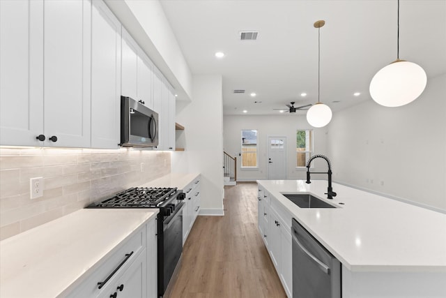 kitchen featuring ceiling fan, sink, hanging light fixtures, stainless steel appliances, and white cabinets