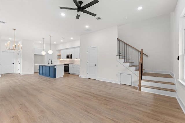 unfurnished living room featuring light hardwood / wood-style floors, ceiling fan with notable chandelier, and sink