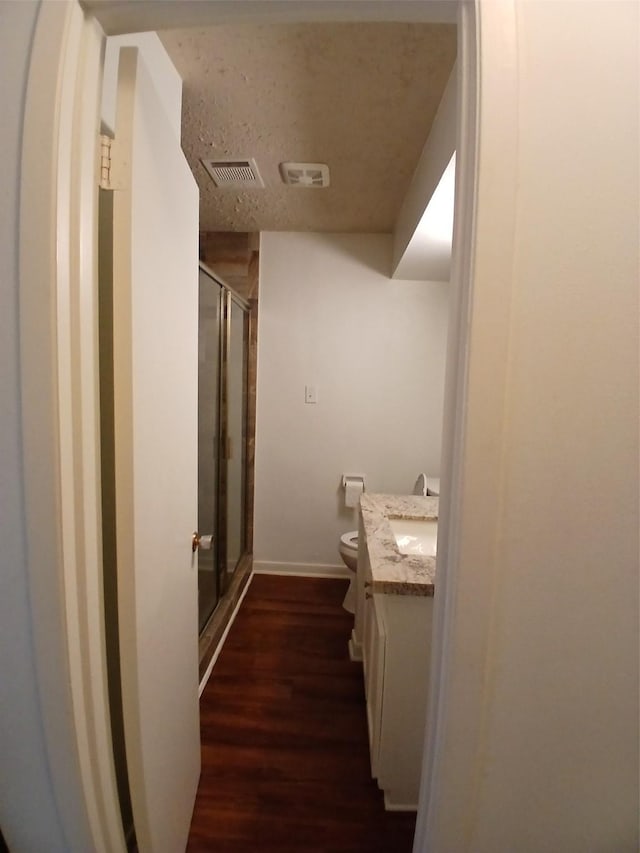 bathroom with wood-type flooring, an enclosed shower, vanity, and toilet