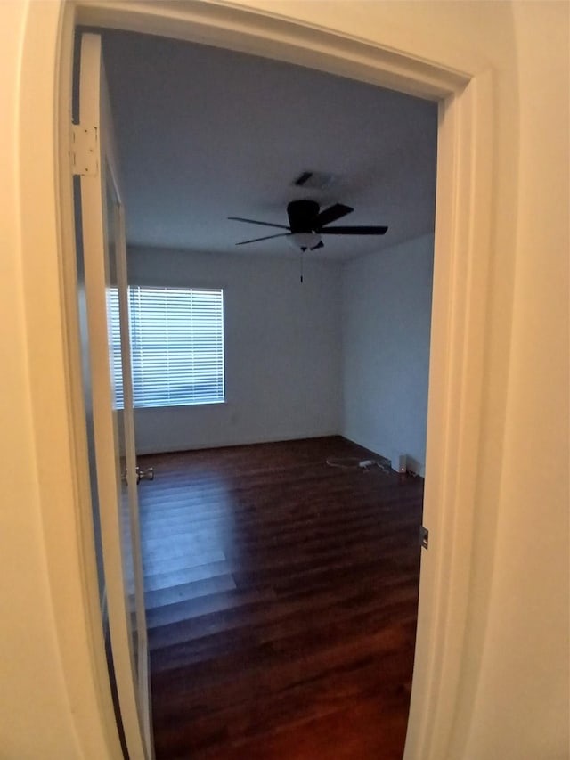 unfurnished room with ceiling fan and dark wood-type flooring