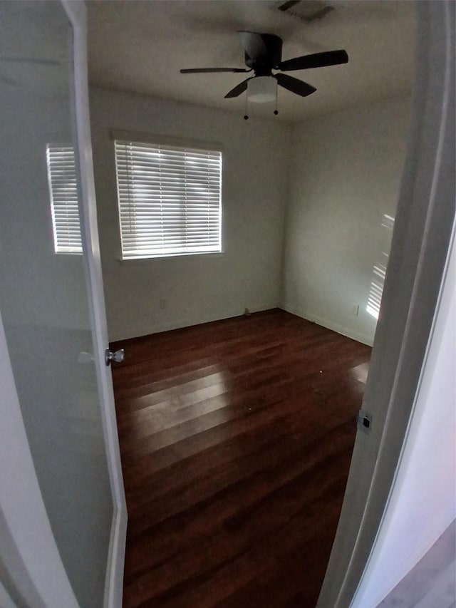 unfurnished room featuring ceiling fan and dark wood-type flooring