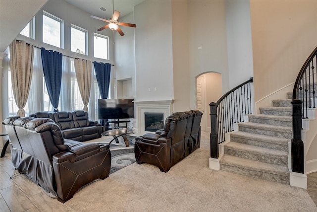 living room featuring ceiling fan, a wealth of natural light, and a towering ceiling