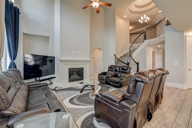 living room featuring a towering ceiling, ceiling fan with notable chandelier, and a tray ceiling