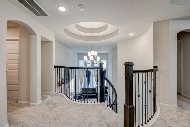 corridor featuring a chandelier, carpet flooring, and a raised ceiling