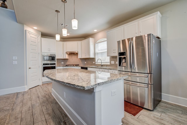 kitchen with stainless steel appliances, white cabinetry, decorative light fixtures, and a center island