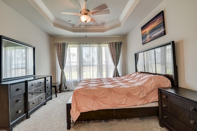 carpeted bedroom with ceiling fan, ornamental molding, and a raised ceiling