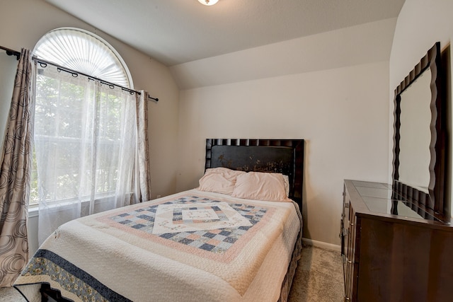 carpeted bedroom featuring vaulted ceiling and multiple windows