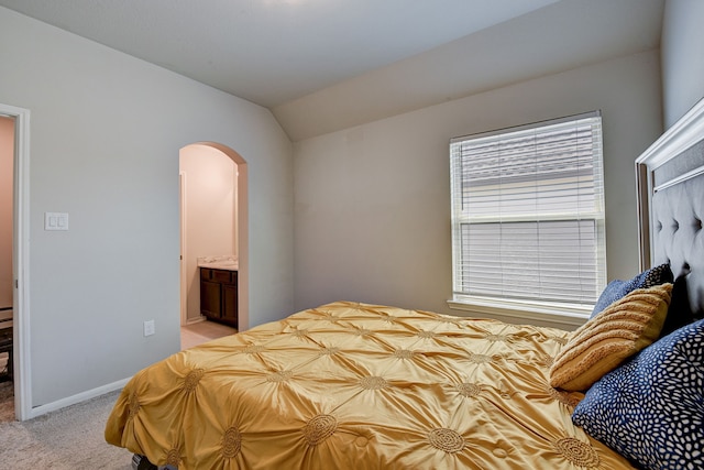 carpeted bedroom featuring lofted ceiling and connected bathroom