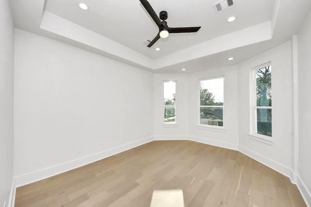 empty room with a tray ceiling and light hardwood / wood-style flooring