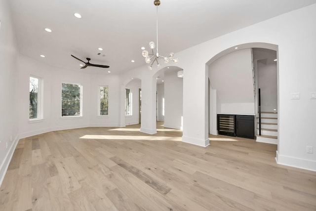 unfurnished living room featuring light wood-type flooring and ceiling fan with notable chandelier