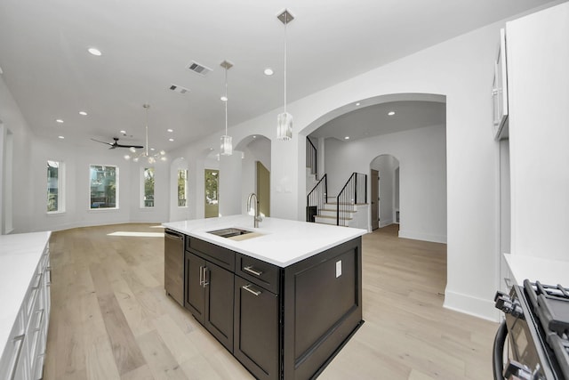 kitchen featuring white cabinetry, gas range, pendant lighting, and sink