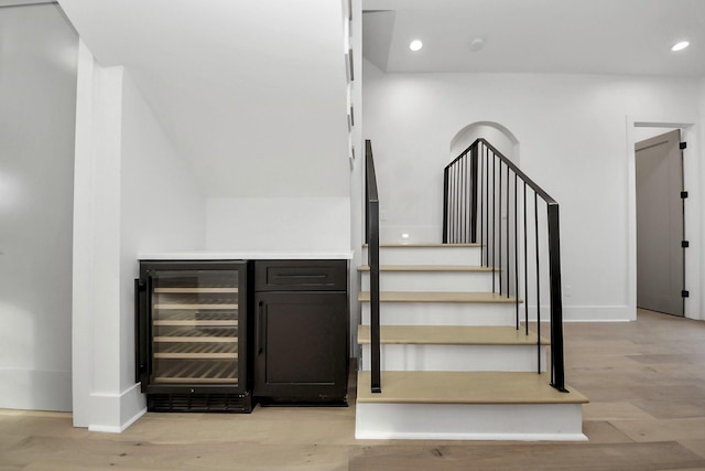 stairs featuring wine cooler, bar, and hardwood / wood-style flooring