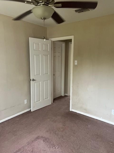 unfurnished bedroom featuring dark colored carpet and ceiling fan