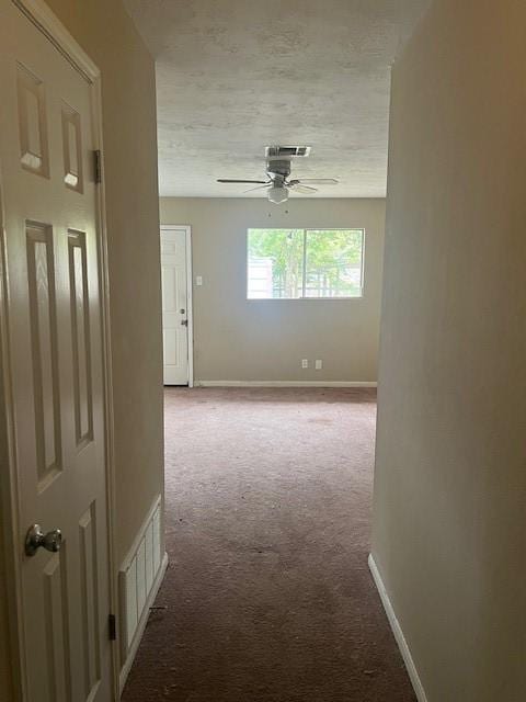 hall featuring light colored carpet and a textured ceiling