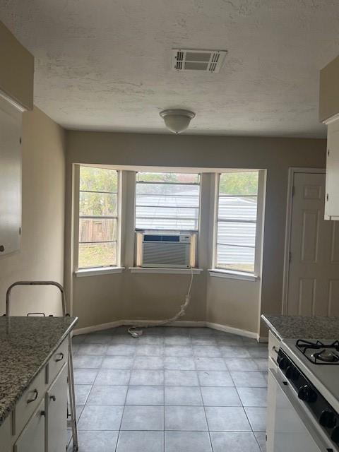 kitchen featuring light stone countertops, light tile patterned floors, white cabinets, and cooling unit