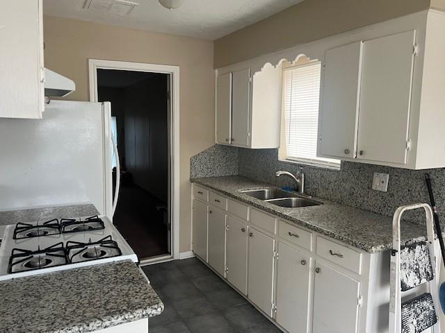 kitchen with tasteful backsplash, sink, white appliances, and white cabinets