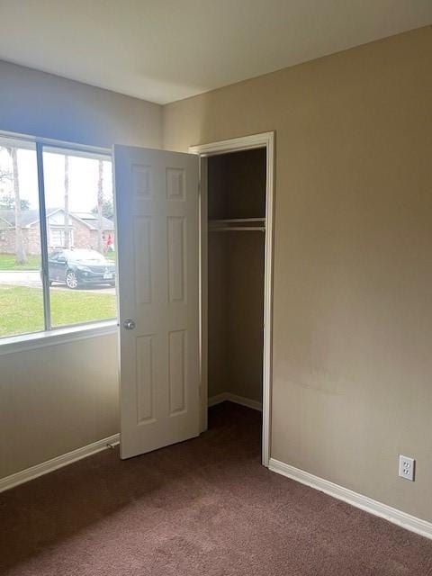 unfurnished bedroom featuring a closet and dark colored carpet