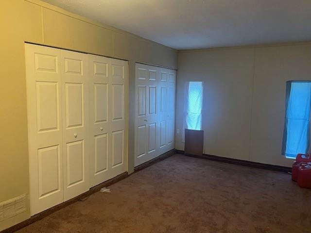 unfurnished bedroom featuring two closets and dark carpet