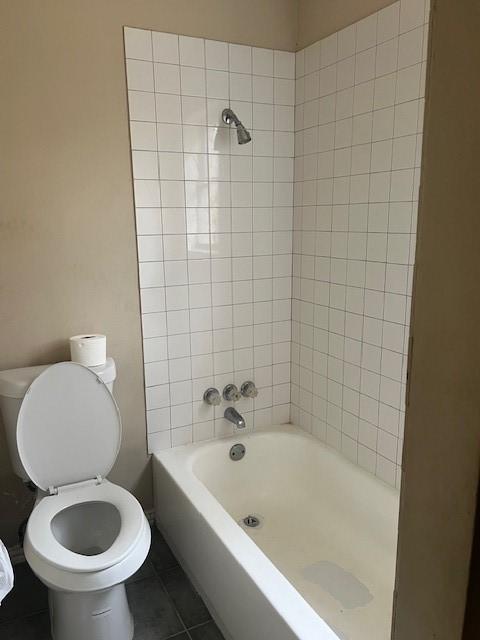 bathroom featuring tiled shower / bath, tile patterned floors, and toilet