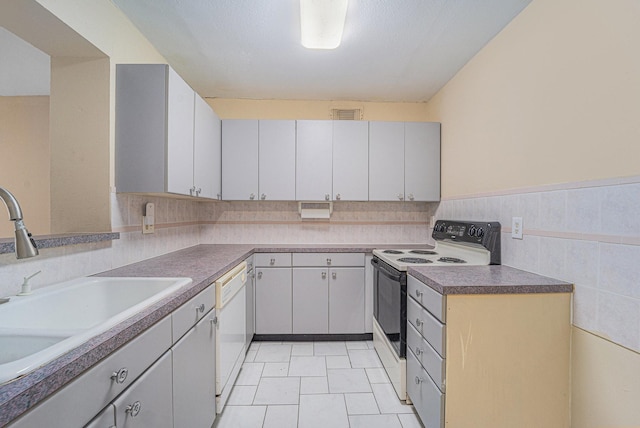 kitchen featuring sink, white appliances, light tile patterned floors, and gray cabinetry