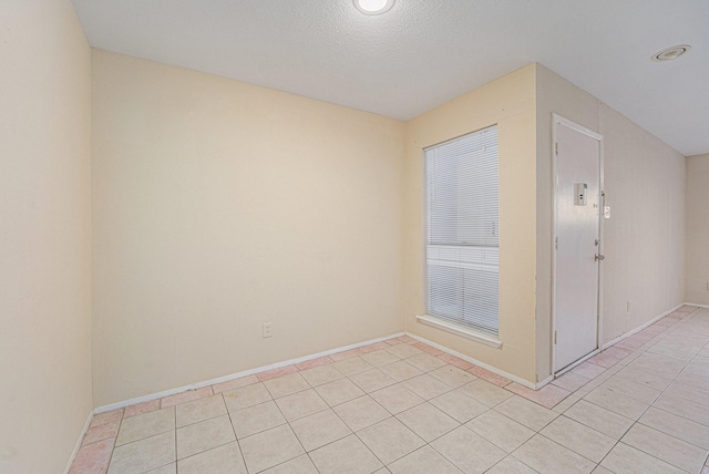 unfurnished room with a textured ceiling and light tile patterned floors