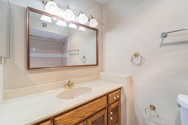 bathroom with toilet, vanity, and tiled shower