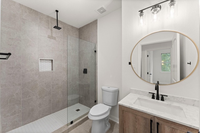 bathroom featuring toilet, a tile shower, tile patterned floors, and vanity