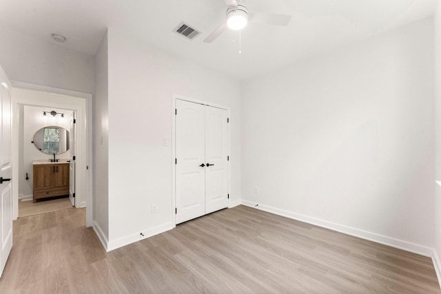 unfurnished bedroom with ceiling fan, a closet, sink, and light hardwood / wood-style floors