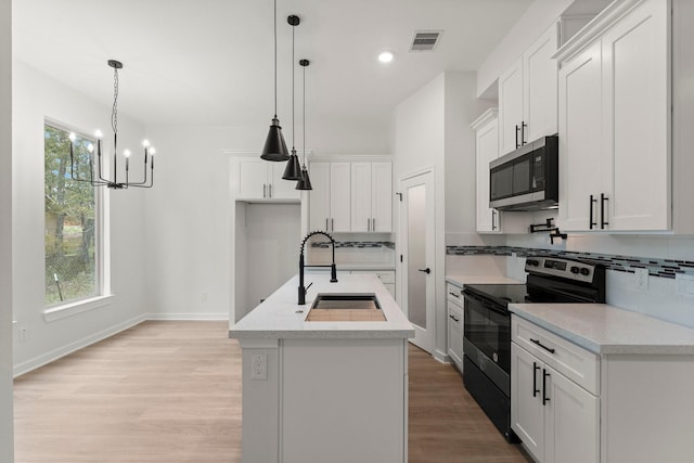 kitchen featuring white cabinetry, an island with sink, decorative light fixtures, electric range oven, and sink