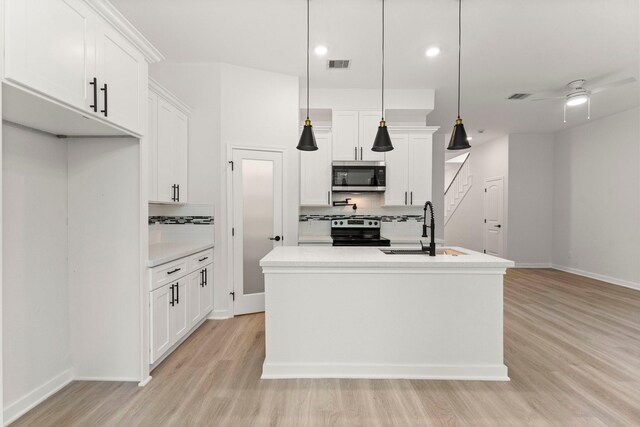 kitchen featuring white cabinetry, stainless steel appliances, sink, hanging light fixtures, and a center island with sink