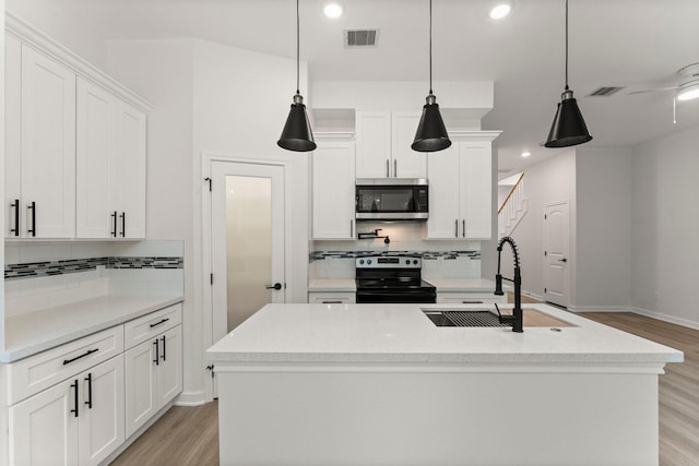 kitchen with black / electric stove, sink, white cabinetry, and pendant lighting