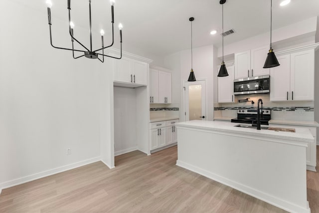 kitchen with tasteful backsplash, white cabinets, a kitchen island with sink, and appliances with stainless steel finishes