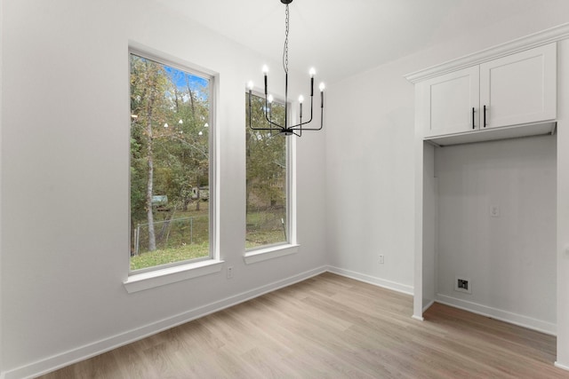 unfurnished dining area with an inviting chandelier and light hardwood / wood-style floors