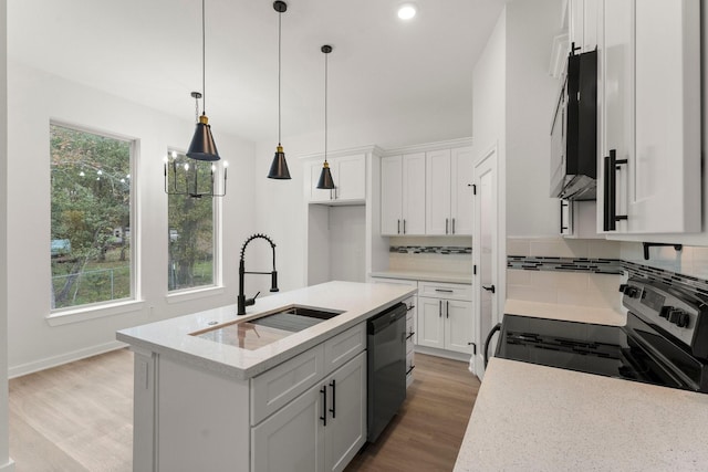 kitchen featuring light stone countertops, appliances with stainless steel finishes, white cabinetry, an island with sink, and sink