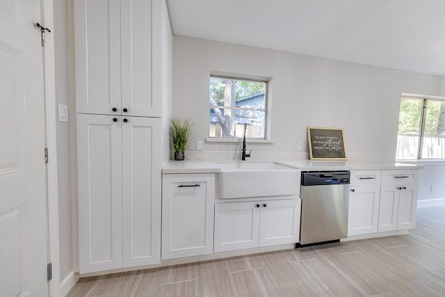 kitchen with stainless steel dishwasher, a wealth of natural light, sink, and white cabinetry