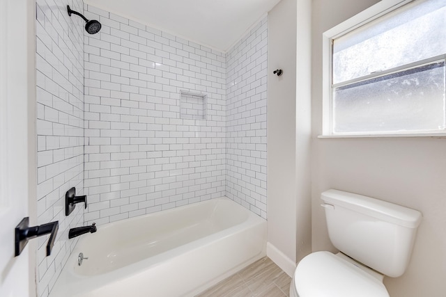 bathroom featuring toilet and tiled shower / bath