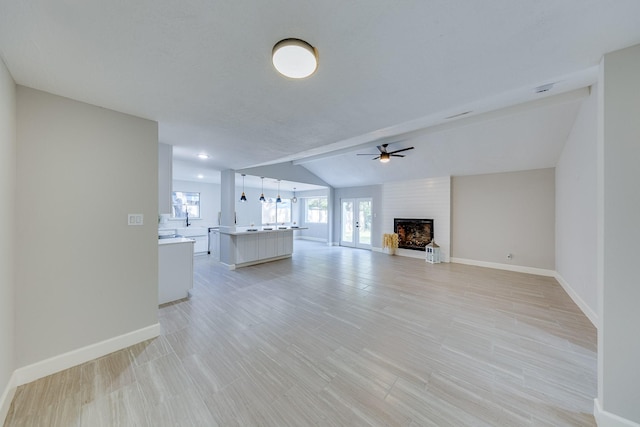 unfurnished living room with lofted ceiling, ceiling fan, and a large fireplace