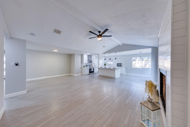 unfurnished living room featuring a textured ceiling, a fireplace, ceiling fan with notable chandelier, and lofted ceiling with beams