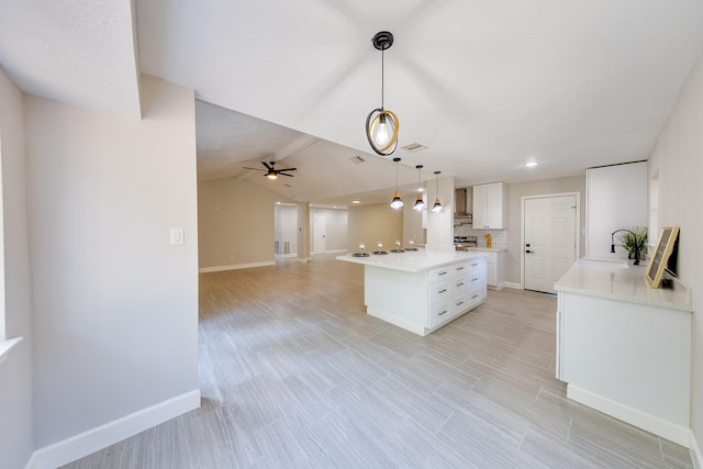 kitchen featuring a kitchen island, decorative light fixtures, white cabinetry, vaulted ceiling, and ceiling fan