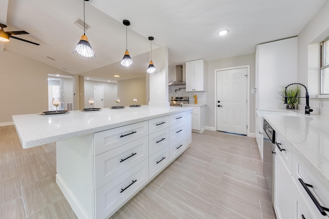 kitchen featuring white cabinetry, appliances with stainless steel finishes, wall chimney exhaust hood, light stone counters, and a center island