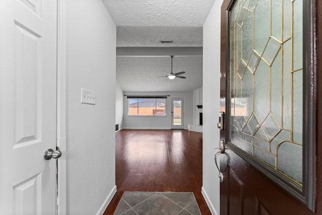 entrance foyer with ceiling fan, a brick fireplace, hardwood / wood-style floors, and a textured ceiling