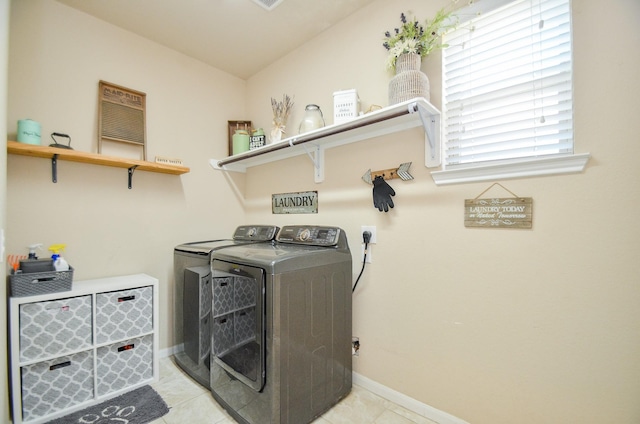 clothes washing area featuring light tile patterned floors and washer and dryer