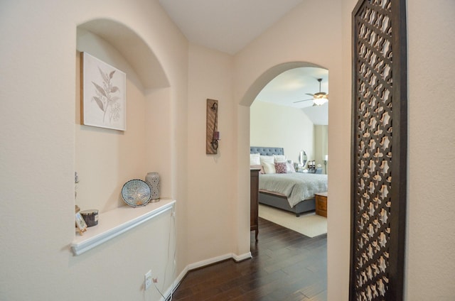 corridor with dark hardwood / wood-style floors and vaulted ceiling